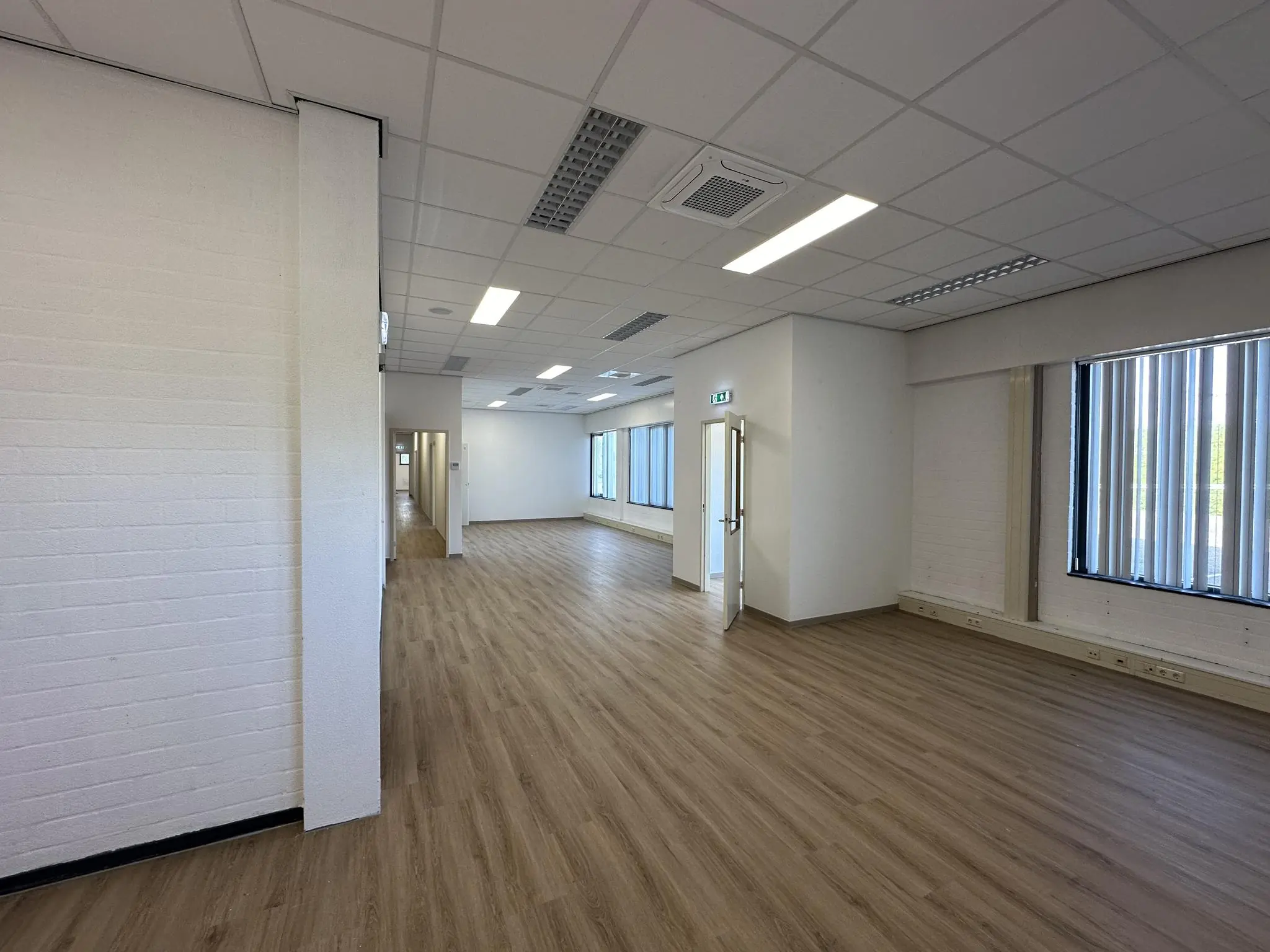 Lichte, lege kantoorruimte aan de Van der Hagenstraat met houten vloer en systeemplafond.